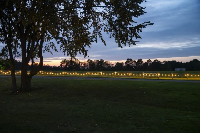 String lights adorn a fence along field